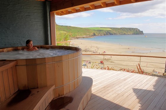 A sheltered hot tub enjoys commanding views over the beach
